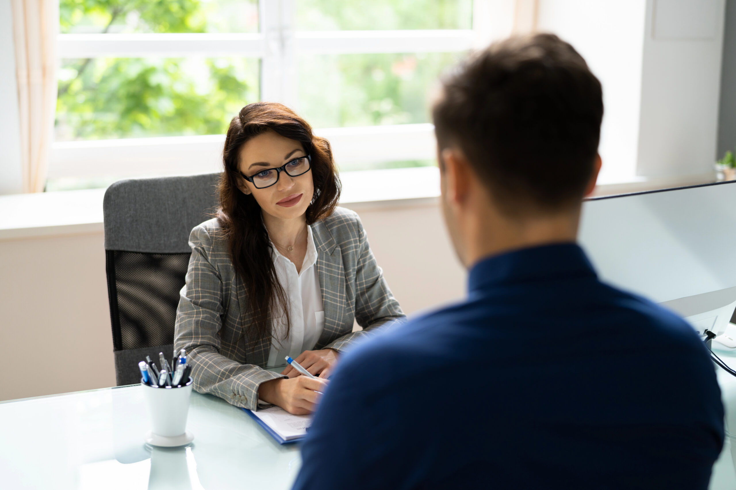 Two professionals having a candid conversation across a table in a modern office, illustrating a senior-level job interview.