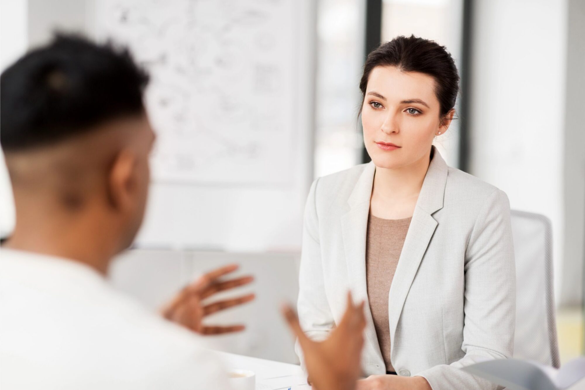 A woman listening attentively to a candidate during a job interview, illustrating the diagnostic value of listening in the first ten minutes.