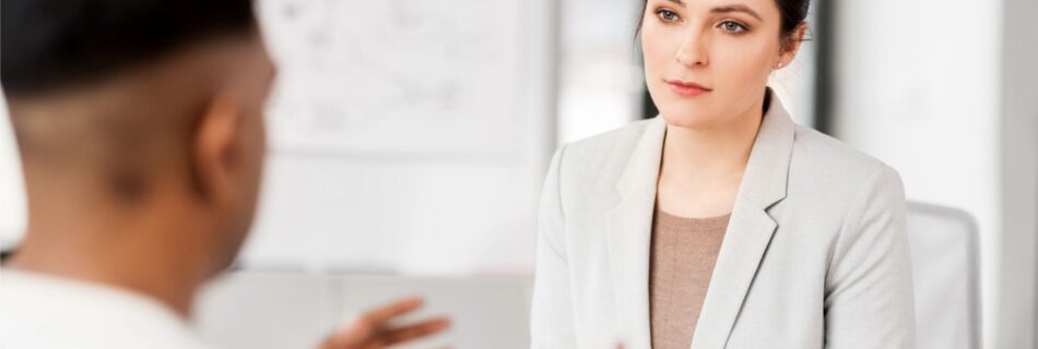 A woman listening attentively to a candidate during a job interview, illustrating the diagnostic value of listening in the first ten minutes.