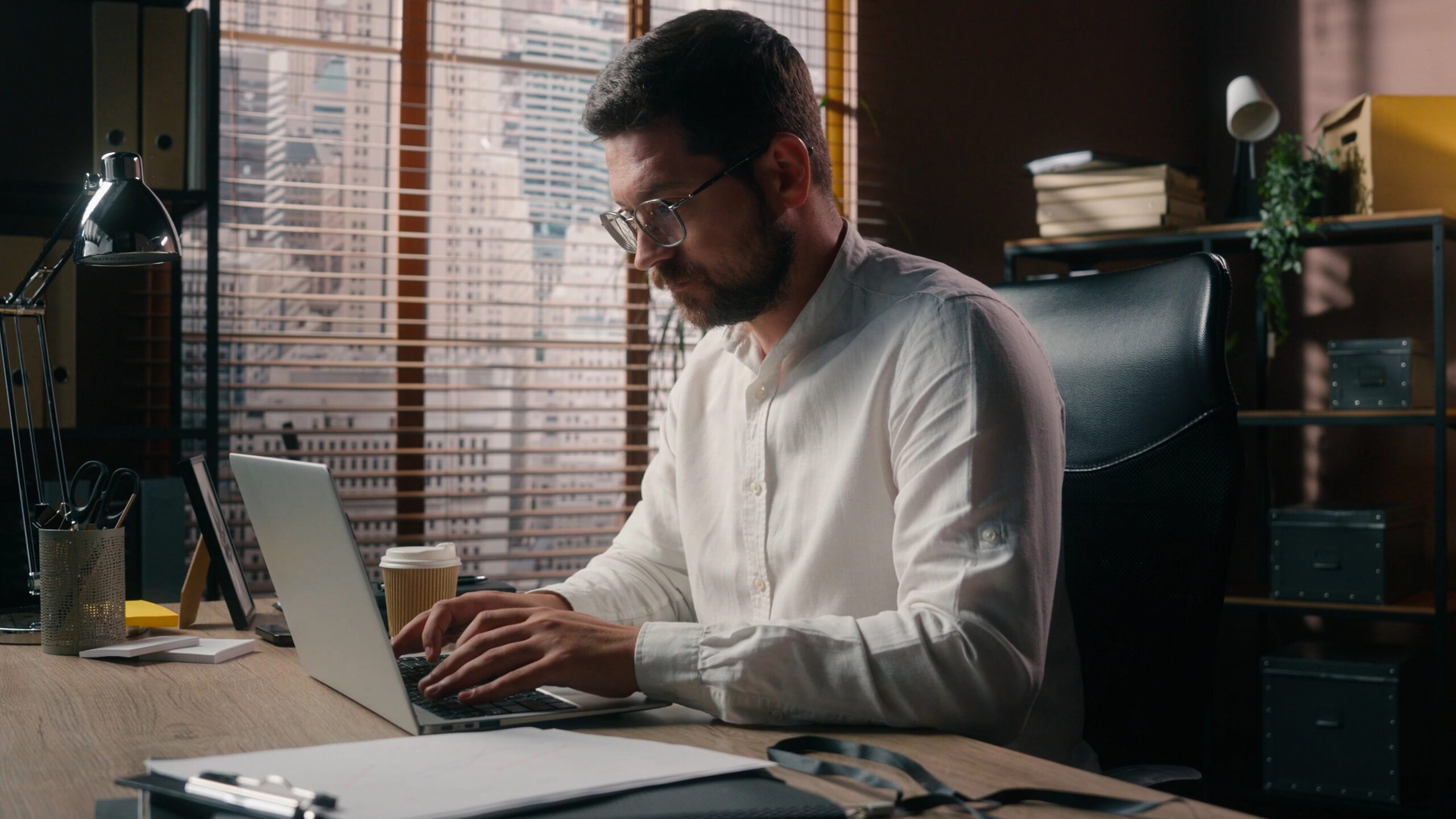 An engineering professional working at a laptop with a drawing set set aside, illustrating the business capabilities required for AEC practice leadership.