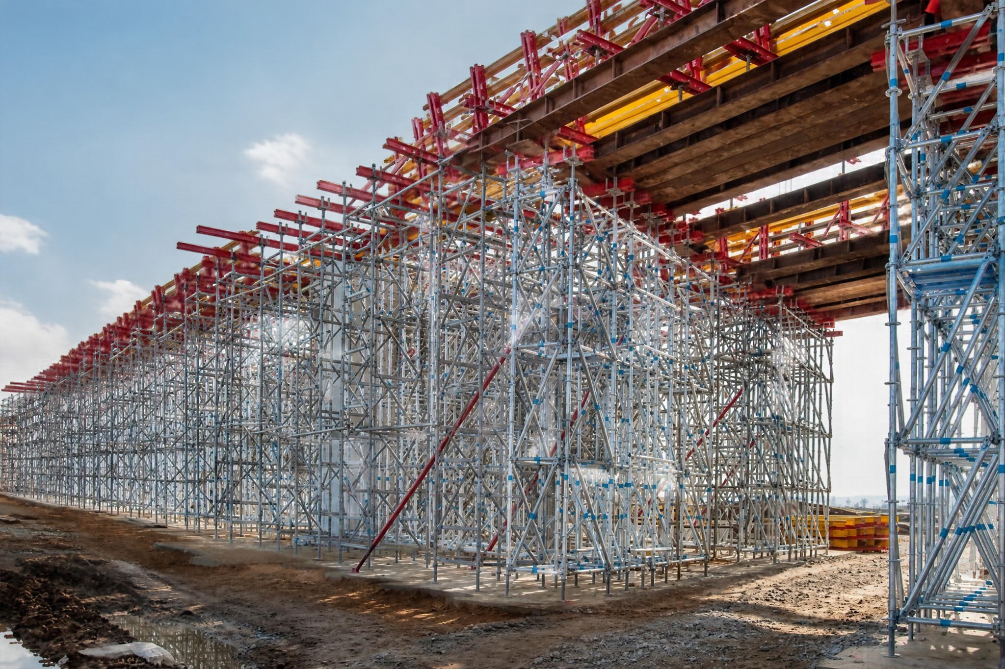 Tall steel shoring towers supporting a bridge deck during construction, with temporary beams and falsework carrying the structure above.